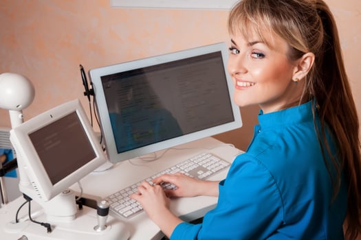 Female Doctor working in a cabinet at the computer and smiling photo