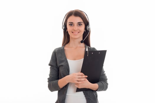 portrait of young call center woman woman with headphones and microphone and board in her hands smiling and looking at the camera isolated on white background photo