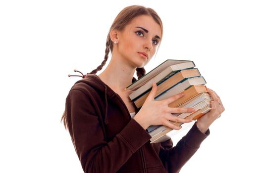tired young brunette student girl in brown sport clothes with a lot of books in her hands posing isolated on white background photo