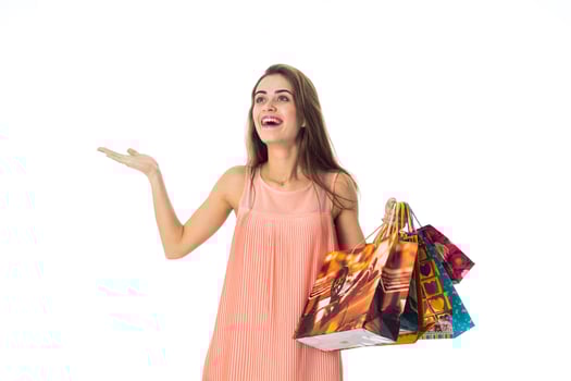 Merry girl spreads her hand and holding large gift bags isolated on white background photo