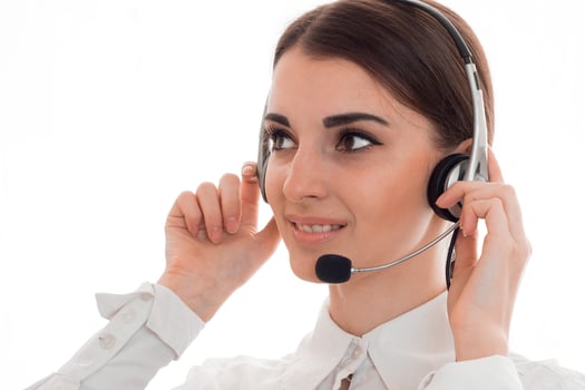 attractive young business woman working in call center with headphones and microphone looking aside and smiling isolated on white background photo