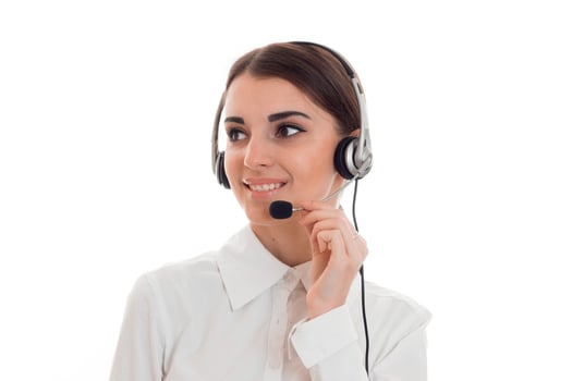 young beautiful brunette business woman with headphones and microphone smiling and looking away isolated on white background photo
