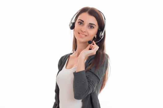 a young girl stands in the headphones with a microphone and looks into a camera photo