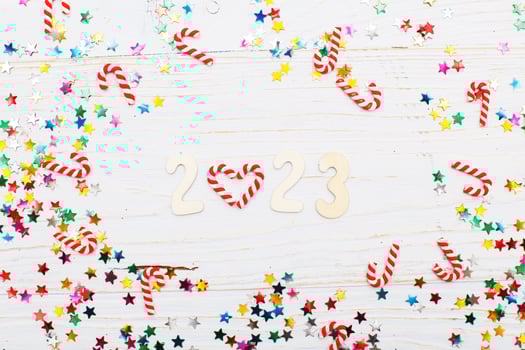 Christmas background with candy canes and multicolored sequins on blue wooden background number 2023 photo