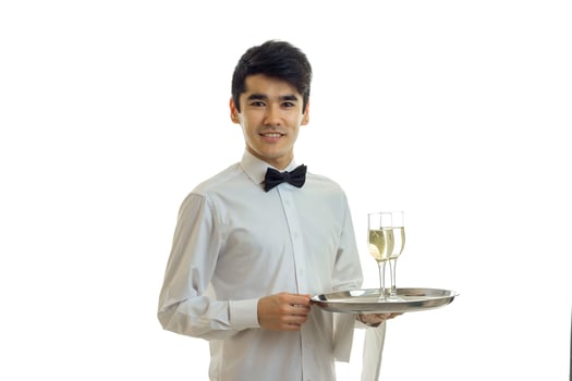 charming young waiter looks straight smiles and holds a tray with glasses photo