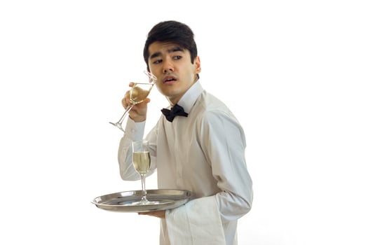 a young waiter in a shirt holding glasses with white wine and looks toward photo