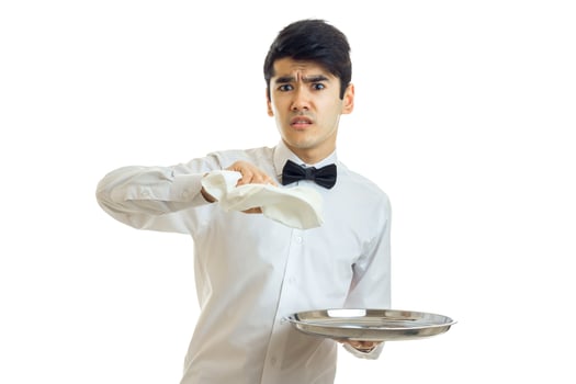 a young waiter in a white shirt with the surprised face holding a napkin and utensil tray photo