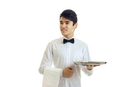 a young guy in a white shirt and black bow tie looks away smiling and holding a towel and tray photo