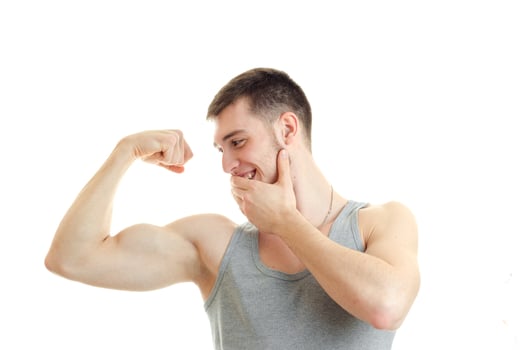 sporty young guy looks on the muscles in the arm and smiling close-up photo