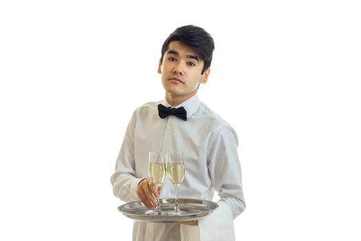 beautiful tired young waiter holding a tray before him with a glass of champagne photo