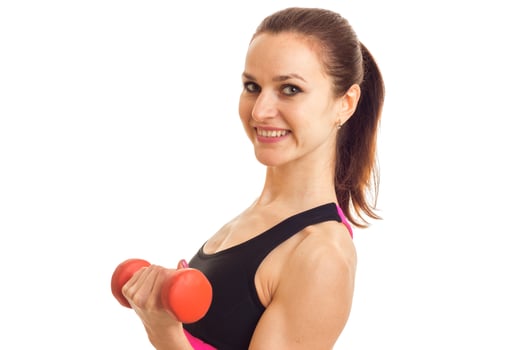 Portrait of a beautiful young girl who smiles with fitness keeps the dumbbell and looks into a camera photo