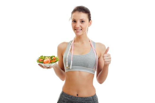 a charming young girl shows a hand gesture and holds a plate of lettuce photo