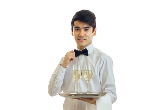 charming young waiter nicely dressed holding a tray with glasses and adjusts his bow tie hand photo