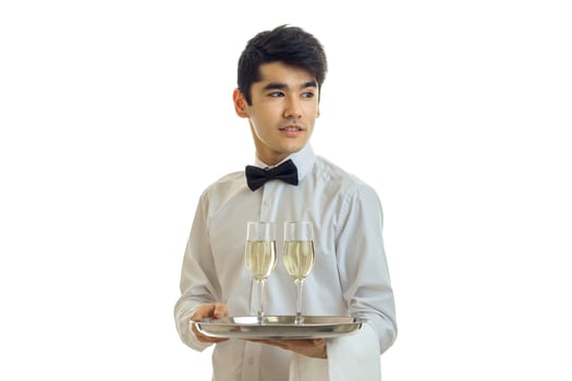 cute young waiter stands unscrewing my head to the side and holding a tray with glasses of champagne photo
