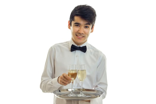 young charming waiter looks straight smiles and holds a tray with two glasses of wine photo