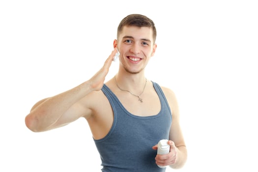 beautiful smiling guy looks forward and deals on face shaving foam close-up photo