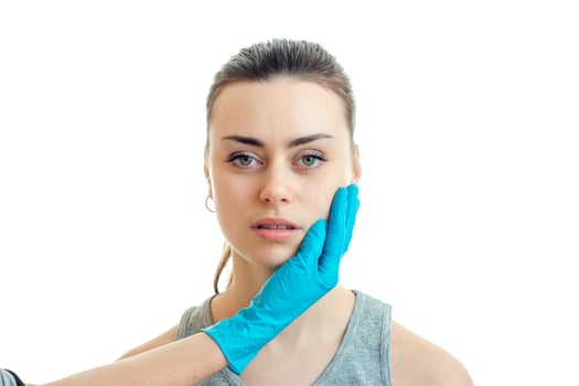 a doctor in a blue glove touches the face young cute girl close-up photo