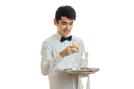 happy young man waiter in uniform with two glasses of wine on silver tray smiling photo