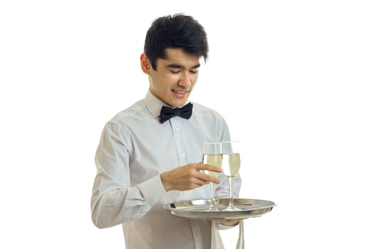 horizontal portrait of attractive smiling waiter who carries a tray with glasses of wine photo