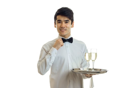 charming young waiter in a beautiful dress looks straight and holding a tray with glasses photo