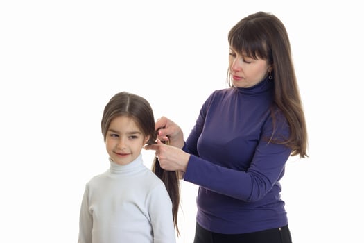 Adult mother makes a hairstyle to her little daughter photo