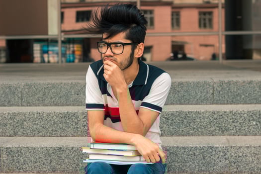 portrait of charming young man in glasses and books photo