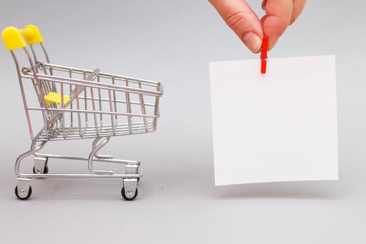 The shopping cart in female hand on grey background photo