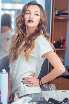 beautiful young girl with curly hairstyle and magenta lips posing across the mirror photo
