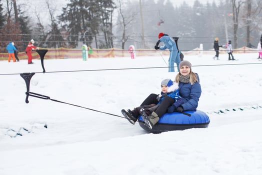 Family having fun on snow tube. mother with kid is riding a tubing. people sliding downhill on tube. ride a lift photo
