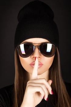 Attractive young female with healthy skin in sunglasses on black background photo