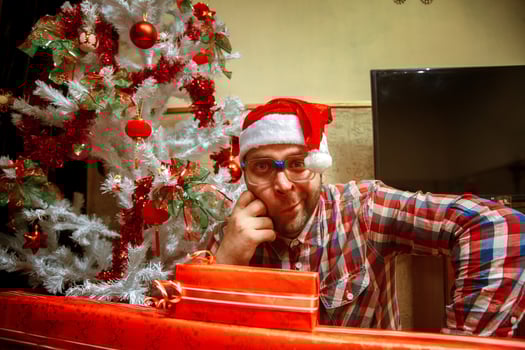 Fun nerd in glasses and santa hat near christmas tree photo