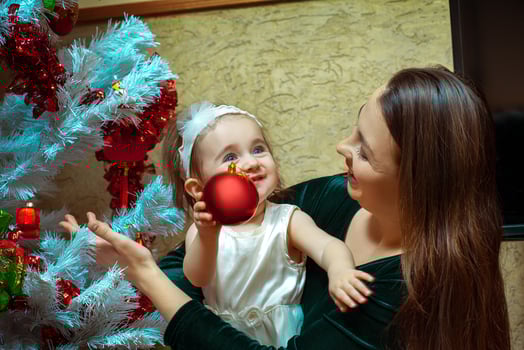 beautiful little baby girl with blue eyes decorates the Christmas tree with her mother photo