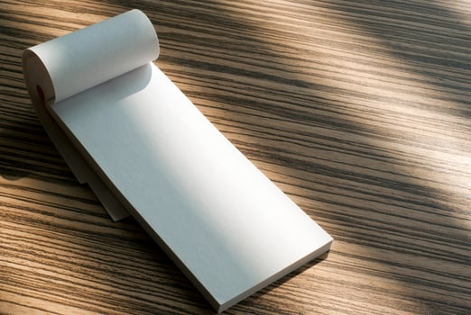 Blank page of writing pad on wooden background photo