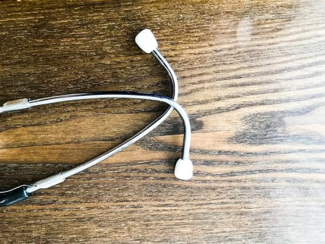 Tubes of a medical stethoscope, phonendoscope for listening to the heart and lungs of sick people on the background of a wooden table photo
