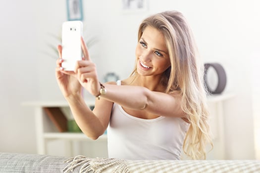 Happy woman with smartphone on sofa photo