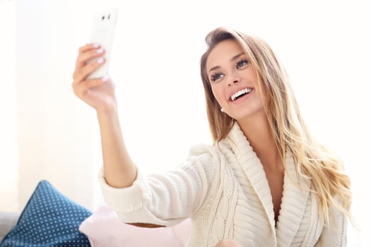 Happy woman taking selfie in bed photo