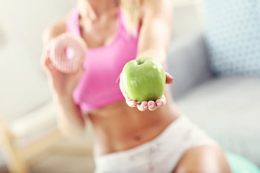 Sporty woman with apple and donut after workout photo