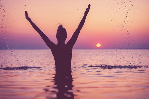 Silhouette of young woman practicing yoga on the beach at sunrise photo