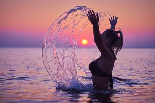Silhouette of young woman practicing yoga on the beach at sunrise photo