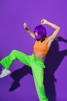 Carefree woman dancer wearing colorful sportswear having fun against purple background photo