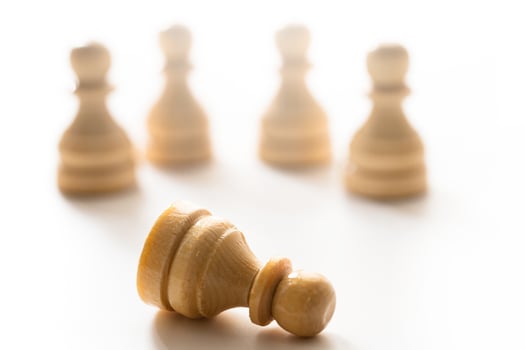 Wooden chessmen standing with one chess pawn lying. photo
