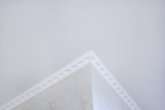 Detail of corner ceiling with intricate crown molding. Suspended ceiling and drywall construction in empty room in apartment or house. Stretch ceiling white and complex shape. photo