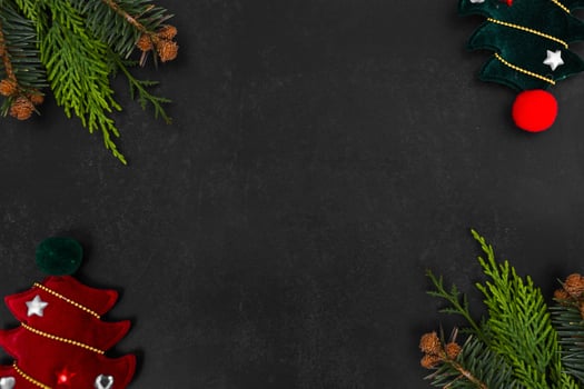 Christmas or New Year dark background with fir branches, Xmas black board framed with season decorations, space for text, view from above. photo