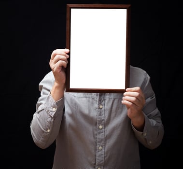 A blank diploma or a mockup certificate in the hand of a man employee wearing shirt on black background. The vertical picture frame is empty and the copy space. photo