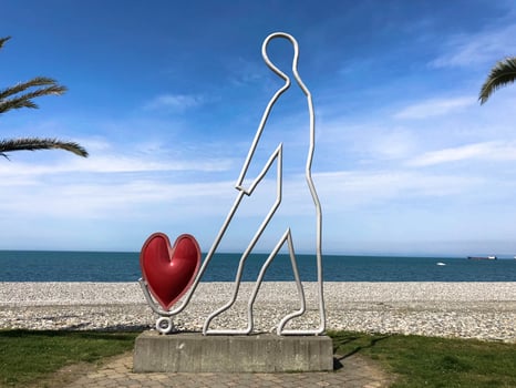 Abstract statues, small architectural forms of a man carrying a heart on a trolley on Batumi Seaside Boulevard or Batumi Beach. Georgia, Batumi, April 17, 2019 photo