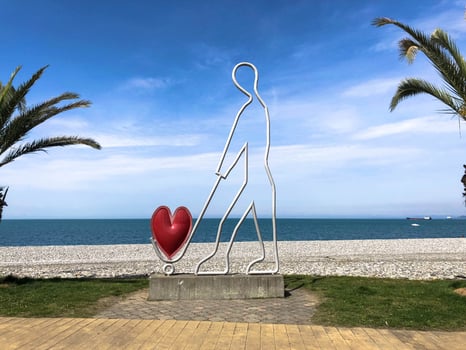 Abstract statues, small architectural forms of a man carrying a heart on a trolley on Batumi Seaside Boulevard or Batumi Beach. Georgia, Batumi, April 17, 2019 photo