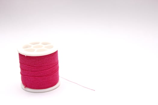 The red thread spool is placed on a white background. photo