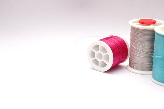 Green, red, colored thread spools placed on a white background. photo