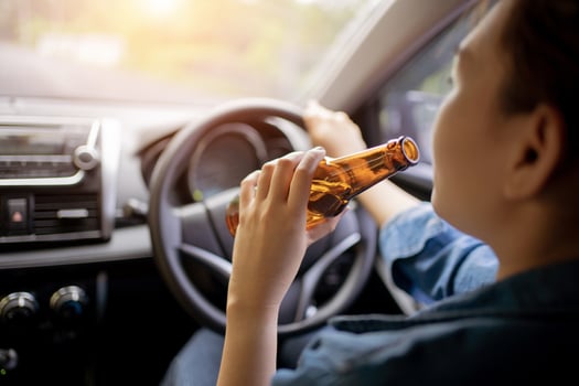Close up of driver and drinking alcohol which Drunk young woman driving a car with a bottle of beer, Drunk driving concept, Don't drink and drive concept. photo
