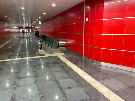 Large red modern long bright underground walkway between metro stations with travel walkers and escalators for quick passage of passengers photo